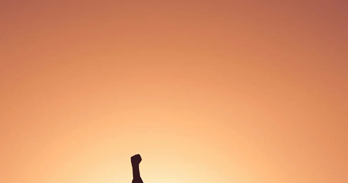 Femme levant le poing devant le soleil couchant - Photo de Miguel Bruna
